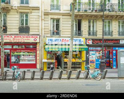 Paris, Frankreich - Mai 12. 2023: Velib-Fahrradverleih vor kleinen Einzelhandelsgeschäften in historischen Gebäuden Stockfoto