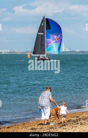 Großmutter mit Enkelin und Hund, die zusammen am Kieselstrand in der Sonne von cowes auf der Insel wight uk spazieren Stockfoto