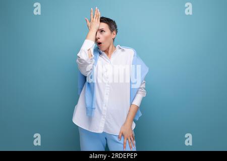 Schockierte junge brünette Frau mit einem kurzen Haarschnitt im weißen Hemd Stockfoto