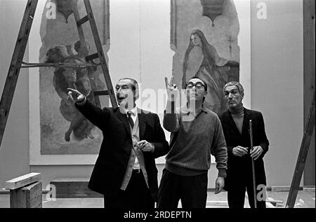 Hayward Gallery London. Carlo Scarpa hängt die Fresken aus Florenz, einer Ausstellung des Arts Council in der Hayward Gallery. Der weltberühmte italienische Architekt Carlo Scarpa (L) weist und gibt Anweisungen. Gesten, während ein anderer Italiener einen zwei-Finger-Salute gibt. London, England ca. 1969 1960S, UK HOMER SYKES Stockfoto