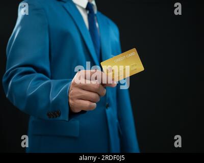 Geschäftsmann mit Kreditkarte auf dunklem Hintergrund. Einkaufskonzept. Bargeldloses Ausgabekonzept. Kreditkonzept Stockfoto