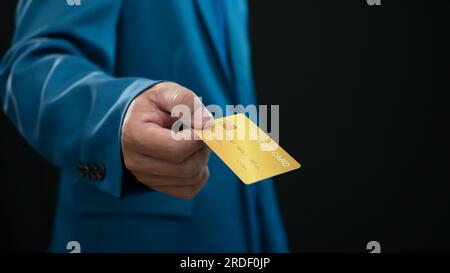 Geschäftsmann mit Kreditkarte auf dunklem Hintergrund. Einkaufskonzept. Bargeldloses Ausgabekonzept. Kreditkonzept Stockfoto