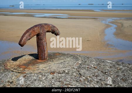 Rostiger Eisenhaken auf einer Betonsäule an einem Strand in der Normandie, Frankreich. Stockfoto