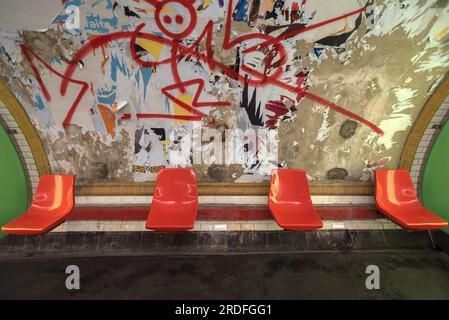 Rote Sitze in der U-Bahn vor einer heruntergerissenen Plakatwand, Paris, Frankreich, heruntergekommen, Graffiti Stockfoto