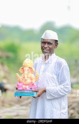 Ein alter indischer Mann, der Lord Ganesha Idol in den Händen hält, ein glücklicher, alter, armer Mann Stockfoto