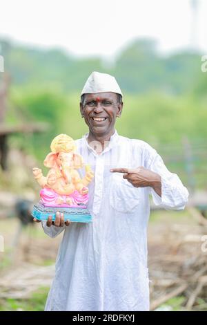 Ein alter indischer Mann, der Lord Ganesha Idol in den Händen hält, ein glücklicher, alter, armer Mann Stockfoto