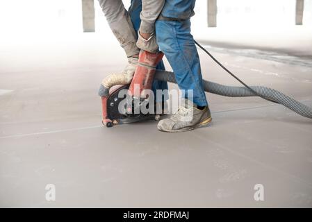 Beim Planieren des Bodens mit der Maschine während der Bauarbeiten anonyme Personen ernten Stockfoto