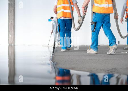 Gruppe von Arbeitern, die Betonboden ausgießen Stockfoto