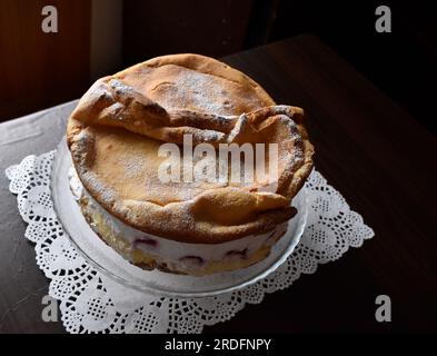 Wunderschöner und köstlicher 'Karpaten'-Kuchen mit Erdbeeren auf einem durchsichtigen Teller auf dem Holztisch mit weißer Teigmasse. Stockfoto