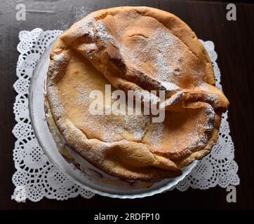 Blick von oben auf den wunderbaren hausgemachten „Karpaten“-Kuchen, dekoriert mit Puderzucker auf einem durchsichtigen Teller und weißem Milieu. Stockfoto