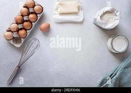Zutaten für das Backen - Karton mit Eiern, Mehl, Zucker und Butter auf Betonhintergrund Stockfoto