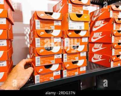 Roppenheim, Frankreich - 11. Juli 2023: Männerhand nimmt rote Boxen mit Nike Laufschuhen aus dem Regal Stockfoto