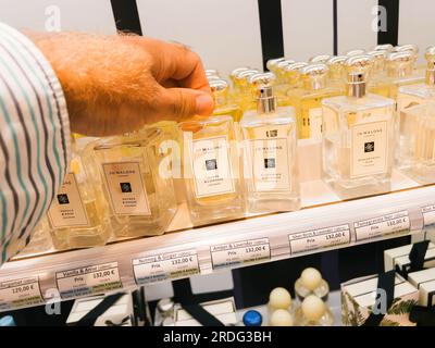 Roppenheim, Frankreich - 11. Juli 2023: Luxuriöser Duft, männliche Hand greift nach einem Jo Malone Parfüm mit Bernstein- und Lavendelduft, bereit zum Kauf im Parfümgeschäft Stockfoto