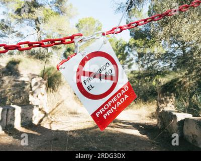 Rotes Warnschild hängt am Baum, sperrt Zugang zu privatem Grundstück in spanischer Sprache - übersetzt als kein unbefugtes Betreten, privatem Grundstück. Ideal für Kommunikationsprojekte im Bereich Sicherheit. Stockfoto