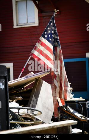20. Juli 2023 Montpelier USA. Nach der Flut, die die Hauptstadt von Vermont, USA, New England, überflutete, ragt eine amerikanische Flagge aus einem Trümmerhaufen in der Langdon Street, Montpelier, VT. Kredit: John Lazenby/Alamy Live News Stockfoto