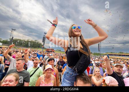 Weeze, Deutschland. 21. Juli 2023. Eine junge Frau feiert auf den Schultern ihres Freundes mit elektronischer Musik. PAROOKAVILLE ist eines der größten Elektro-Festivals in Europa. Das Konzept hinter dem Festival ist eine Stadt, die nur zum Feiern erbaut wurde. Kredit: Christoph Reichwein/dpa/Alamy Live News Stockfoto