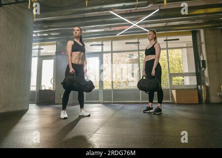 Gruppe sportlicher Frauen im Aerobic-Unterricht, die Bag-Squat-Übungen im Fitnessstudio durchführen Stockfoto
