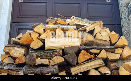 Brennholz auf einem Haufen vor einem Tor im Hof. Stockfoto