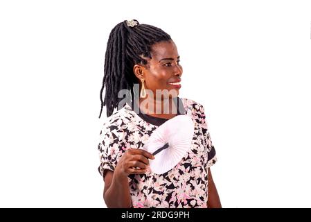 Porträt einer schönen, reifen Frau, die sich mit einem Ventilator bläst, während sie zur Seite blickt. Stockfoto