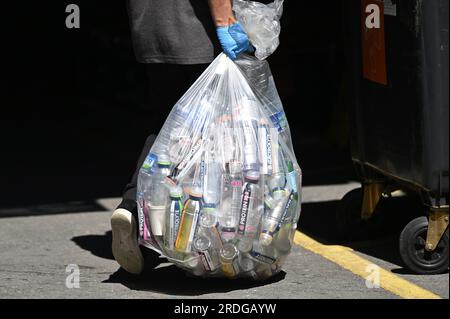 Ein Arbeiter trägt eine Plastiktüte voller leerer Plastikflaschen in Fulham, Süd-London. 21. Juli 2023. Stockfoto