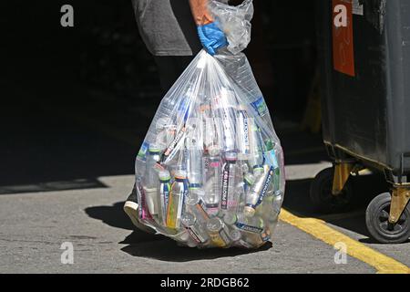 Ein Arbeiter trägt eine Plastiktüte voller leerer Plastikflaschen in Fulham, Süd-London. 21. Juli 2023. Stockfoto