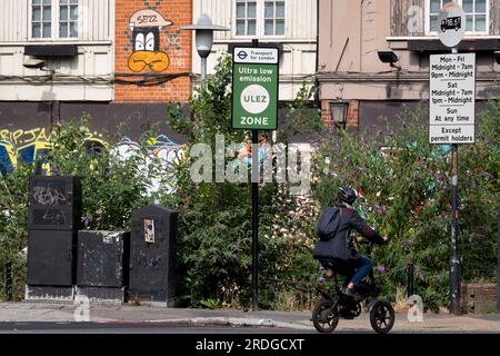 Ein Radfahrer fährt am 21. Juli 2023 in London, England, an einem ULEZ-Schild (Ultra Low Emission Zone) am South Circular in East Dulwich vorbei. Das neue ULEZ-Gebiet ist jetzt 18-mal größer und verbietet ältere Fahrzeuge wie umweltschädliche Dieselfahrzeuge und Benzinfahrzeuge über 2006 Jahre, ein Versuch, giftige Emissionen zu senken, die die Gesundheit von 1 von 10 Kindern, die an Asthma leiden, weiter schädigen. Fahrer von nicht befreiten Fahrzeugen können nach Zahlung einer Tagesgebühr von £12,50 USD in die ULEZ einreisen – oder sie müssen eine Gebühr von £160 USD zahlen. Stockfoto