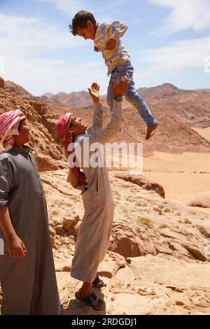 Beduinenjunge, der ein kleines Kind in die Luft wirft, Wadi Rum, Aquaba, Jordanien Stockfoto