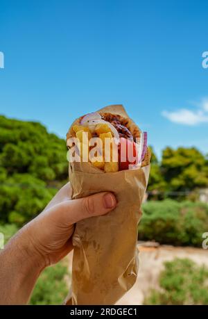 Mann mit griechischem Pita Gyros oder Schawarma mit pommes frites. Straßenküche. Stockfoto