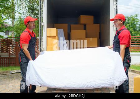 Sorgfältige Mitarbeiter entladen Gegenstände aus einem Lkw und bereiten sich sorgfältig darauf vor, sie in ein neues Haus zu bringen. Ihr effizientes Teamwork sorgt für einen reibungslosen Transport Stockfoto