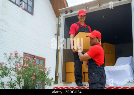 Sorgfältige Mitarbeiter entladen Gegenstände aus einem Lkw und bereiten sich sorgfältig darauf vor, sie in ein neues Haus zu bringen. Ihr effizientes Teamwork sorgt für einen reibungslosen Transport Stockfoto