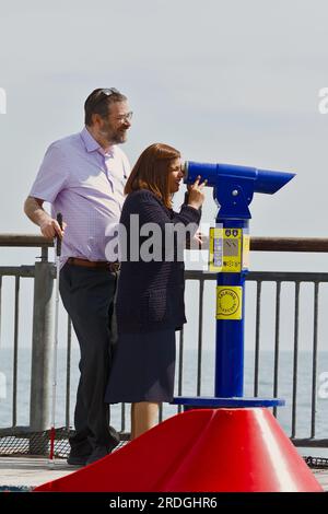 Mann und sehbehinderte Frau, die Ein münzbetriebenes sprechendes Teleskop benutzt, um die Aussicht am Ende des Bournemouth Pier, Großbritannien, zu beschreiben Stockfoto