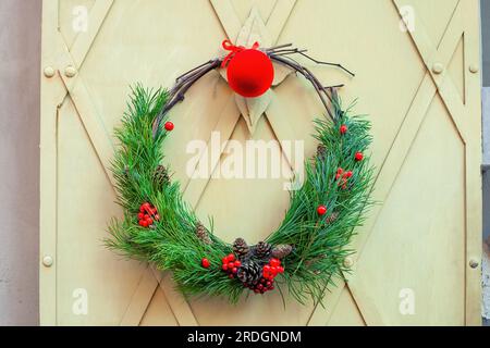 Weihnachtstraditionskranz, Kugeln hängen an den Fensterläden des Hauses. Traditioneller rustikaler Xmas-Kranz mit Fichtenzweigen, dekorierter con Stockfoto