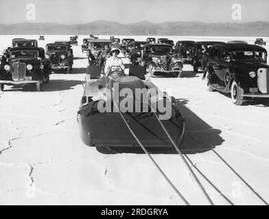 Bonneville Salt Flats, Utah: 3. September 1935 Sir Malcolm Campbells Bluebird Rennwagen wird für seinen ersten Probelauf auf die Salzberge gezogen, um einen neuen Geschwindigkeitsrekord von 300 km/h zu erreichen. Die große Autoseskorte ist im Hintergrund. Stockfoto