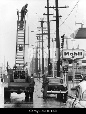 Kalifornien: ca. 1955 Uhr Ein Hilfsteam, das an einem regnerischen Tag an einem Stadtsortiment arbeitet. Stockfoto