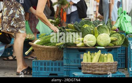 Besucher des traditionellen Bauernmarktes in Prag Naplavka, die Frau im Vordergrund, die aus einem Haufen Gemüse auswählt. Stockfoto