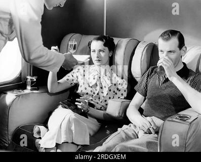 London, England: c. 1936 Ein Paar genießt Cocktails in der Raucherlounge des neuen Fluggastschiffes Imperial Airways Empire. Stockfoto