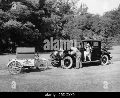 Kalifornien: ca. 1925 Ein Mechaniker der California State Automobile Association, der einer Frau hilft, die in einem Auto eine Panne hatte. Stockfoto