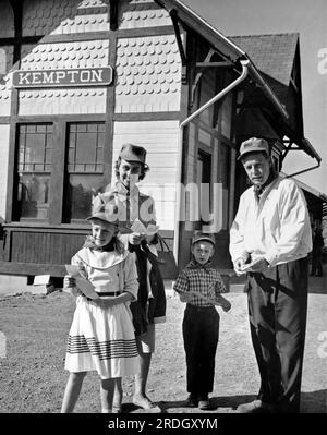 Kempton, Pennsylvania: c. 1963 Eine vierköpfige Familie hat die Tickets und die Schutzkappen des Ingenieurs und wartet am Bahnhof auf eine Fahrt mit dem Zug. Stockfoto