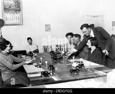 Los Angeles, Kalifornien: 21. November 1927 Führerscheinbewerber in Los Angeles müssen zunächst ihre Kenntnisse über den Verkehr unter Verwendung von Modellautos auf einem Tisch mit einer Miniaturverkehrsszene auf einer Straße nachweisen. Hier entwirrt der Prüfer eine trügerische Marmelade und verrät den potenziellen Fahrern, wie es passiert ist. Stockfoto