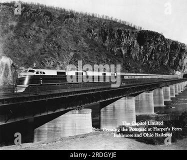 Harpers Ferry, West Virginia c. 1951 Baltimore und Ohio Railroad's Capitol Limited Personenzug, der den Potomac River auf einem Stützpunkt bei Harpers Ferry überquert. Stockfoto