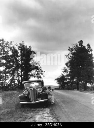 Chautauqua Lake, New York: 1936 Ein Autofahrer parkt in der Abenddämmerung am Straßenrand und genießt die Landschaft und den Rauch seiner Pfeife. Stockfoto