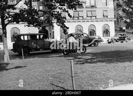 Vereinigte Staaten: c. 1936 Ein Motorradpolizist sitzt im Schatten am Straßenrand und wartet darauf, dass ein Autofahrer das Gesetz bricht. Stockfoto