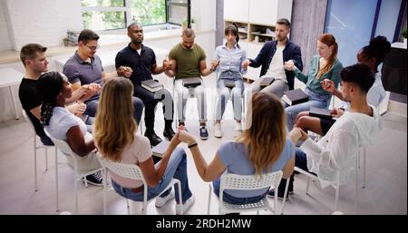 Gruppe von Menschen sitzen gemeinsam Beten mit Bibel Stockfoto