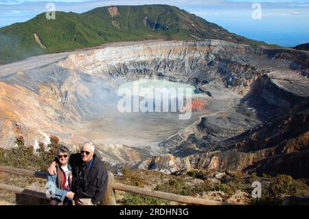 Ein pensioniertes amerikanisches Paar besucht den Poas Volcano National Park in Costa Rica. Der vulkanische See im Hintergrund heißt Laguna Caliente. Robuster volcan Stockfoto