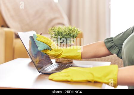 Reinigung, Laptop und Hände der Frau zu Hause mit Gummihandschuhen für Hygiene, Desinfektion und Waschen. Reinigungsservice, Housekeeping und Schließung Stockfoto