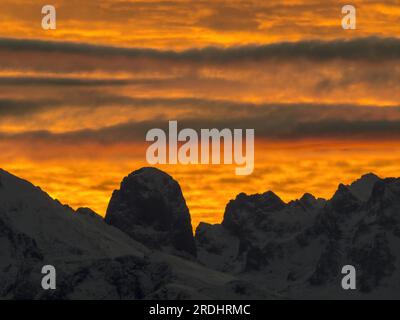 Die abgerundete Silhouette von Naranjo de Bulnes, inmitten der anderen Berge des Picos de Europa, die sich vor dem Himmel eines spektakulären Sonnenuntergangs erheben. Stockfoto