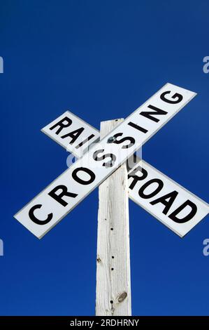 Strahlend blauem Himmel Rahmen rustikal Bahnübergang unterzeichnen. Low Angle Shot mit viel blauem Himmel anzeigen und kopieren. Stockfoto