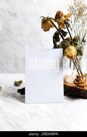 Mustervorlage mit verwelkten Rosen mit einer leeren Karte auf Marmorhintergrund. Vorlage für Designer. Vorderansicht. Stockfoto