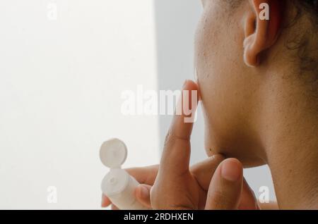 Nahaufnahme der Frauenhände, die die Gesichtshaut mit feuchtigkeitsspendender Creme pflegen, tief nährend sind und ein Gefühl von Frische und Glätte vermitteln. Stockfoto