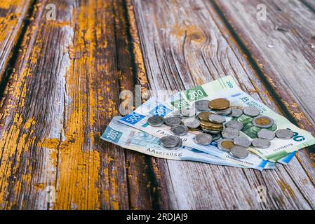 Ein Stapel mexikanischer Münzen und Scheine auf einem Holztisch. Stockfoto